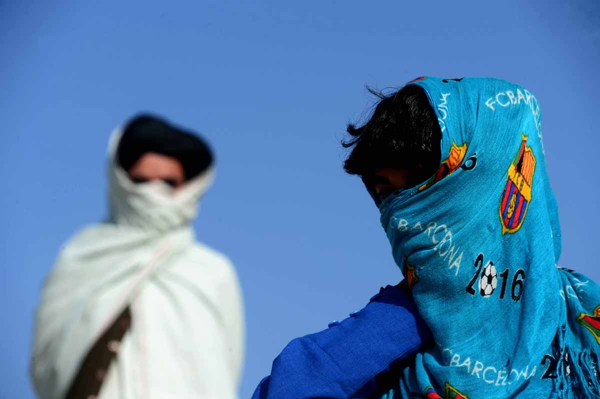 This file photo taken on October 31, 2016 shows an Afghan boy (R), who was held as a child sex slave, as he walks with a relative at a unidentified location in Afghanistan.