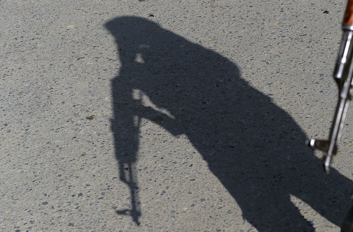 The shadow of an Afghan policeman falls onto the ground as he keeps watch near the largest US military base in Bagram, 50 km north of Kabul, after an explosion on November 12, 2016.
