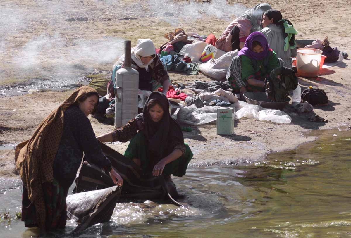 Afghani women with uncovered faces wash their clothes on the bank of Kabul river 15 November 2001. The Northern Alliance, which swept into Kabul 13 November, Afghani women with uncovered faces wash their clothes on the bank of Kabul river 15 November 2001. The Northern Alliance, which swept into Kabul 13 November,
