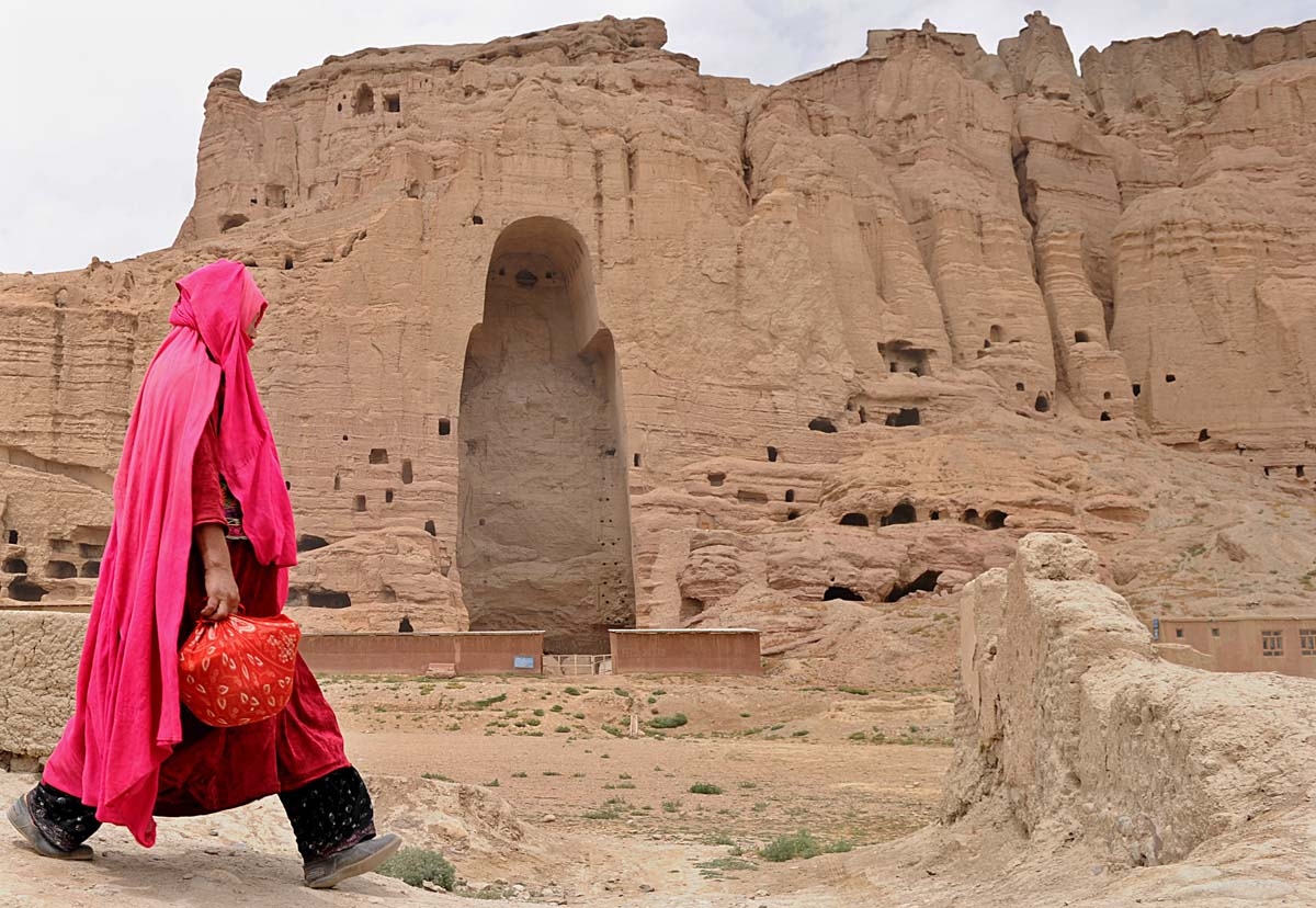 In this file photo taken on August 1, 2010 a Hazara Afghan woman walks past the ruins of the ancient Buddha statues that once stood in the city of Bamiyan. Agence France-Presse's chief photographer in Kabul, Shah Marai, was killed April 30