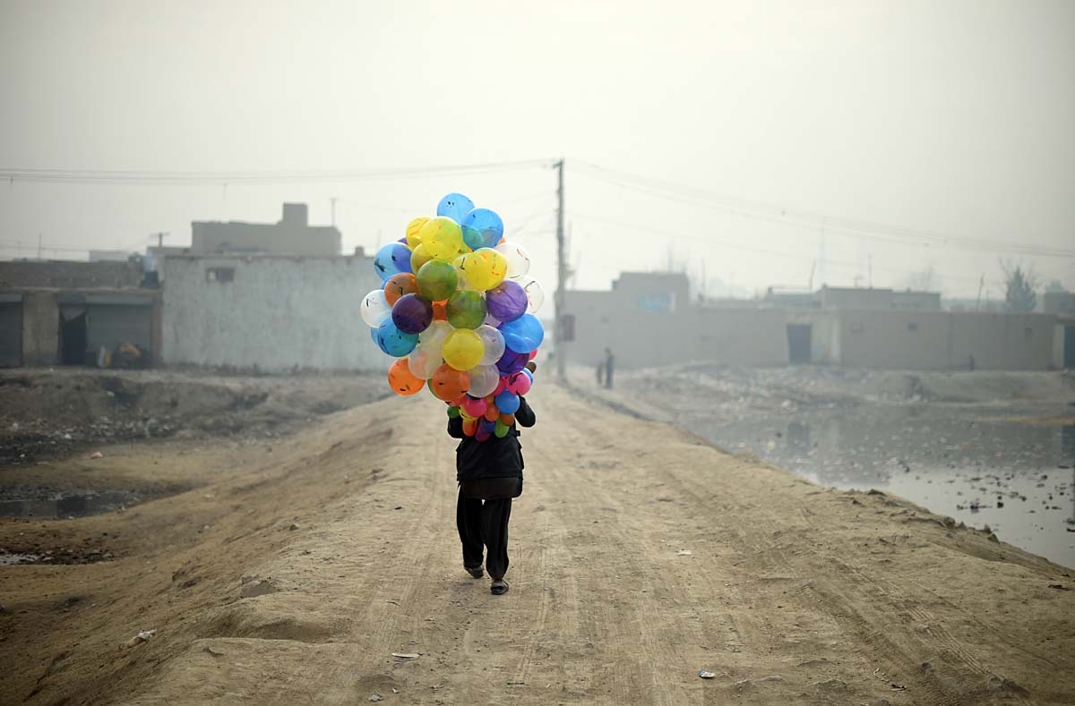 Afghan balloon vendor Arash, 19, waits for customers as he walks through a neighbourhood in Kabul on January 12, 2015. Arash sells balloons for 5 Afghani, which is the equivalent to less then one US cent, makes around 4 USD per day when business is good.