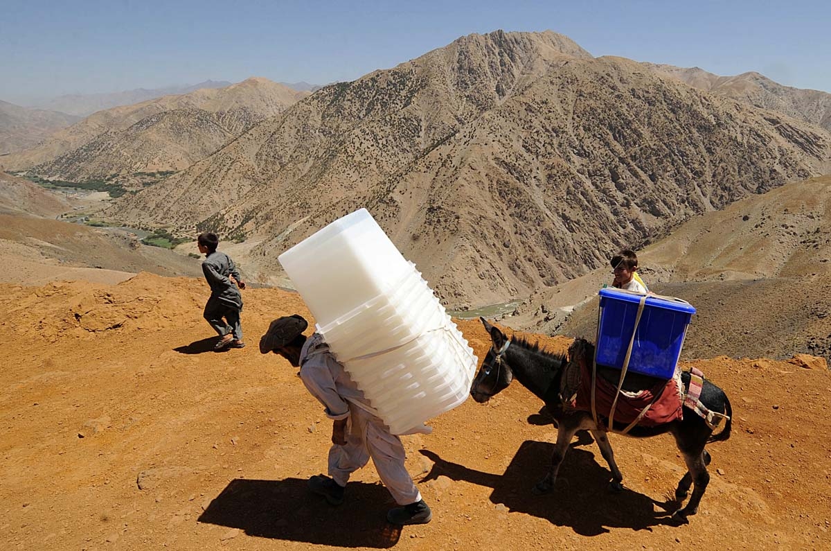 An Afghan man carries ballot boxes as he guides his donkey carrying election supplies in the rugged mountains of the Panjshir valley on August 19, 2009.