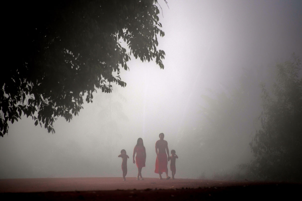 Jawaruwa Waiapi and his family walk amidst fog, early in the morning, at the Manilha village in the Waiapi indigenous reserve in Amapa state in Brazil on October 13, 2017.