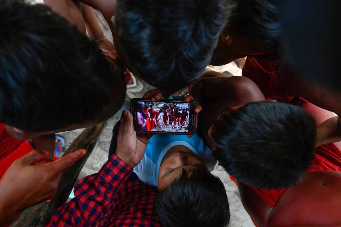 Waiapi children watch a video of a traditional Waiapi dance in a mobile phone at the Manilha village at the indigenous reserve Waiapi in Amapa state in Brazil on October 12, 2017.