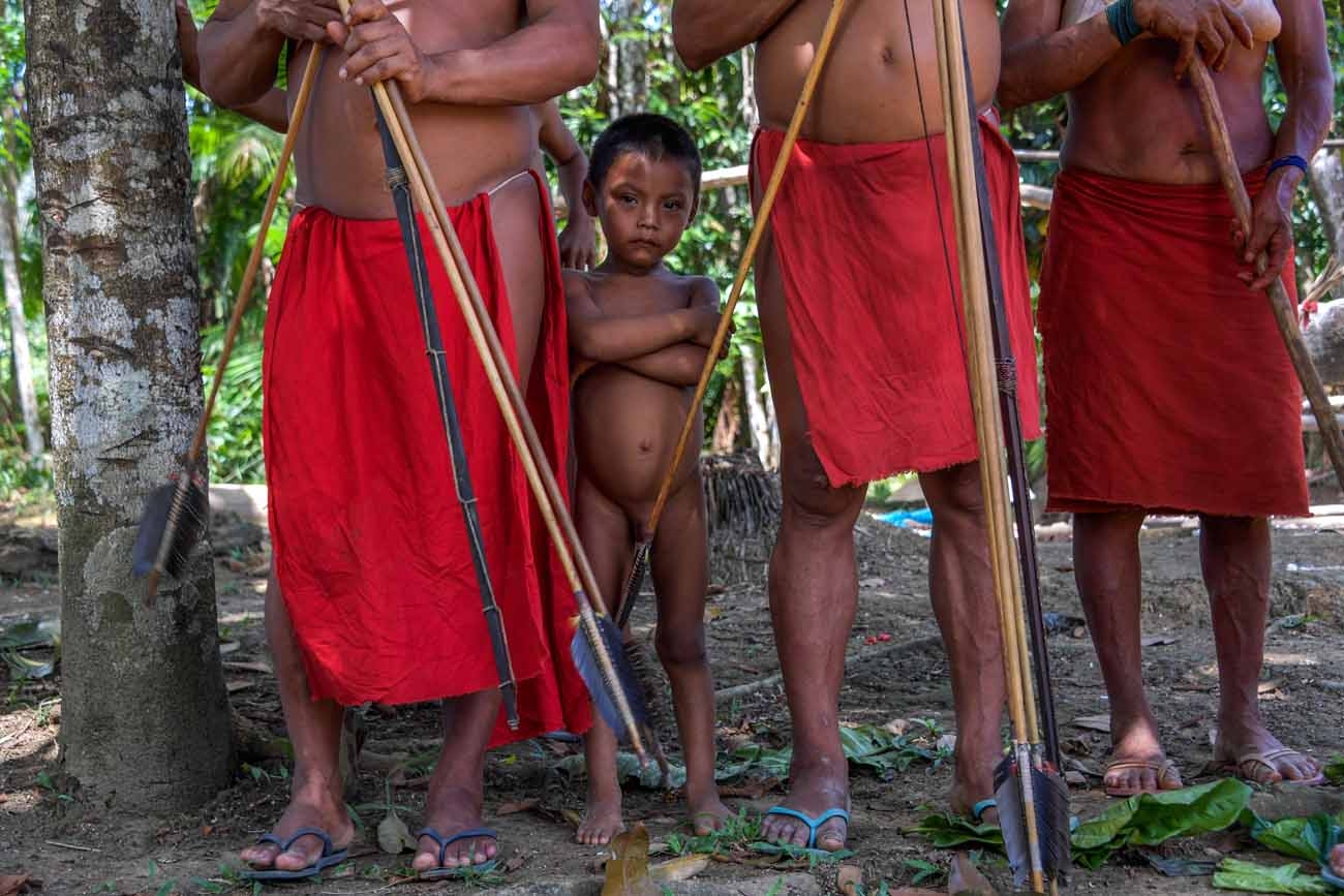 A Waiapi boy stands behind adults at the Pinoty village in Waiapi indigenous reserve in Amapa state in Brazil on October 12, 2017.