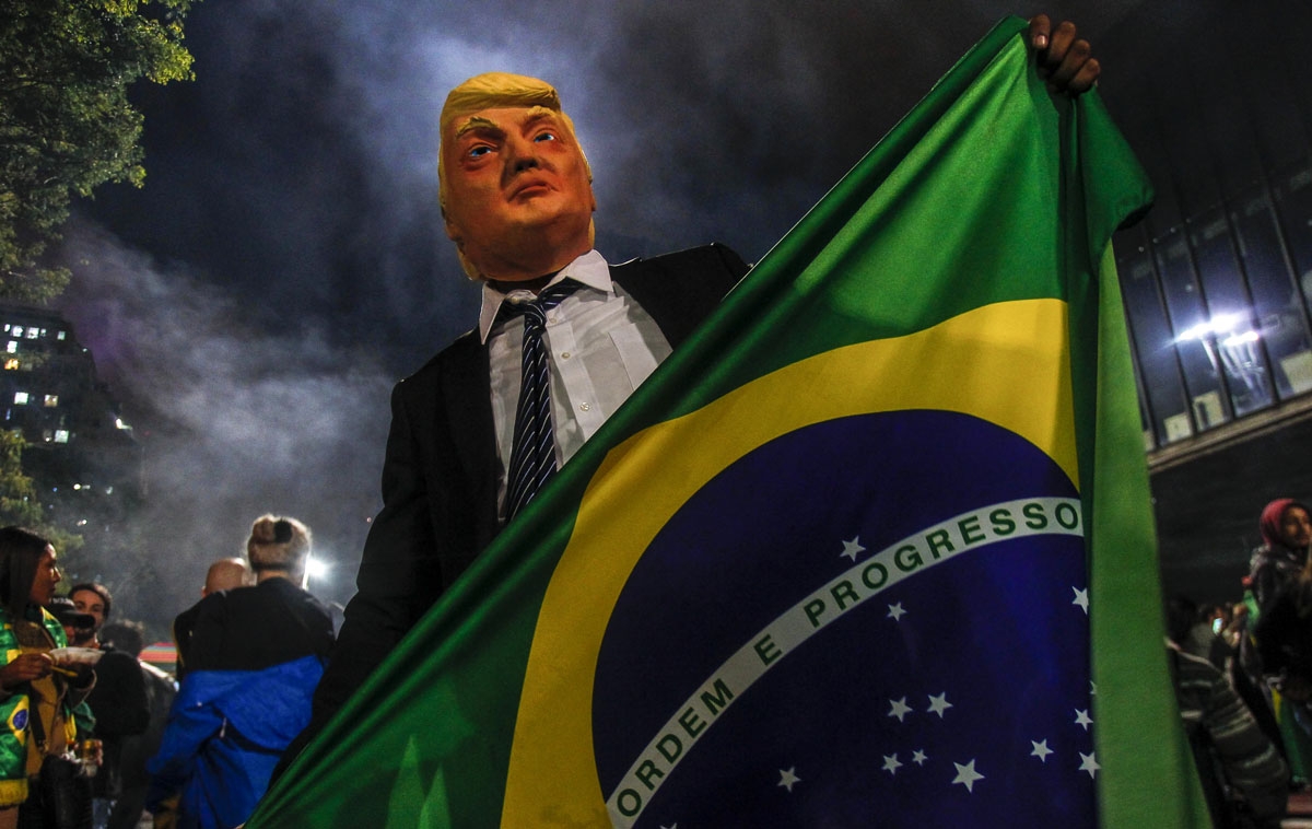 A supporter of far-right lawmaker and presidential candidate for the Social Liberal Party (PSL), Jair Bolsonaro, wears a mask of US President Donald Trump as he celebrates after Bolsonaro won Brazil's presidential election, in Sao Paulo, Brazil, on Octobe