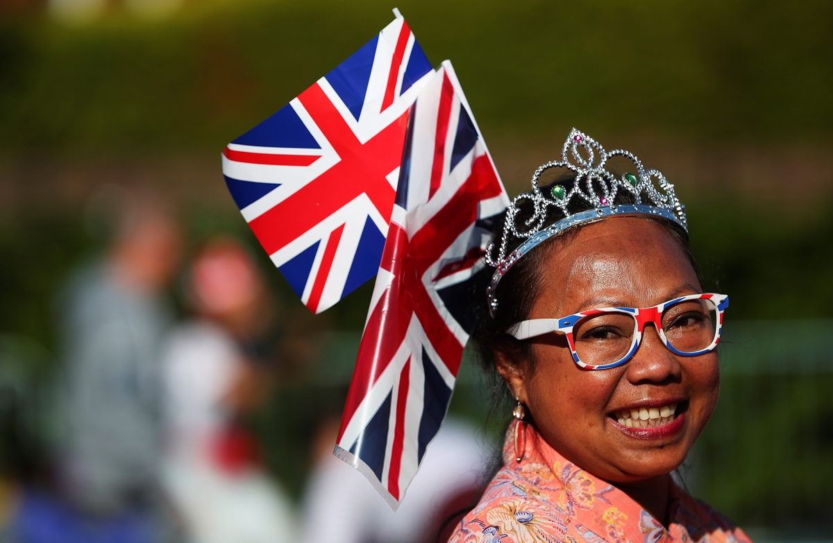 A well-wishers waves a Union flag as she waits on the Long Walk leading to Windsor Castle ahead of the wedding and carriage procession of Britain's Prince Harry and Meghan Markle in Windsor, on May 19, 2018. / AFP PHOTO / POOL / HANNAH MCKAY