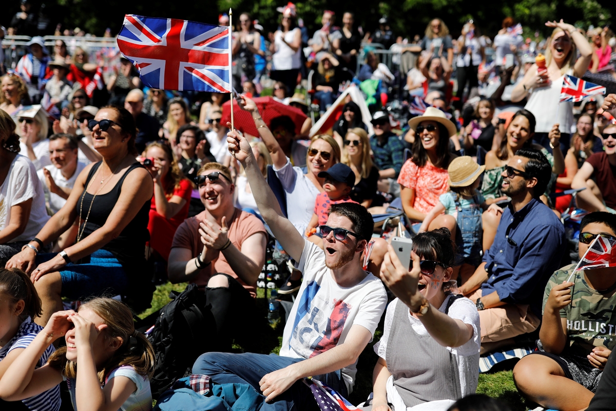 Well-wishers watch a giant screen broadcasting the wedding ceremony of Britain's Prince Harry, Duke of Sussex and Meghan Markle in Windsor, on May 19, 2018. / AFP PHOTO / Tolga AKMEN