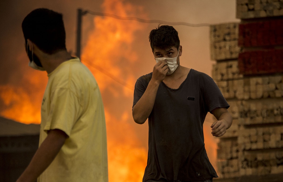 Men wear face masks during a forest fire in Constitucion, 359 km south of Santiago, on January 26, 2017.