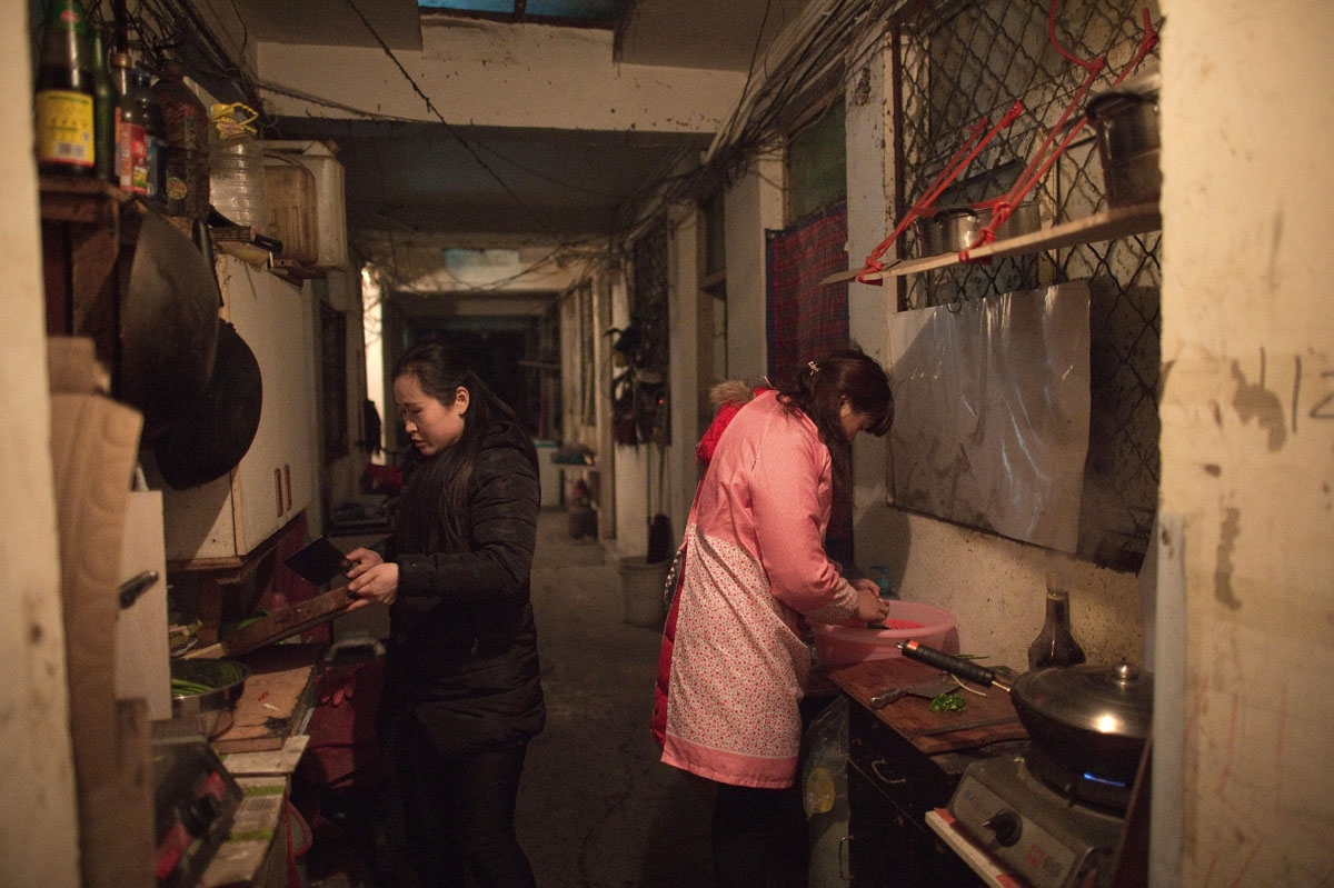 This picture taken on February 15, 2017 shows women cooking in the corridor, where they share a stove and a sink with their neighbours, of a building in the Heiqiaocun migrant village in Beijing.