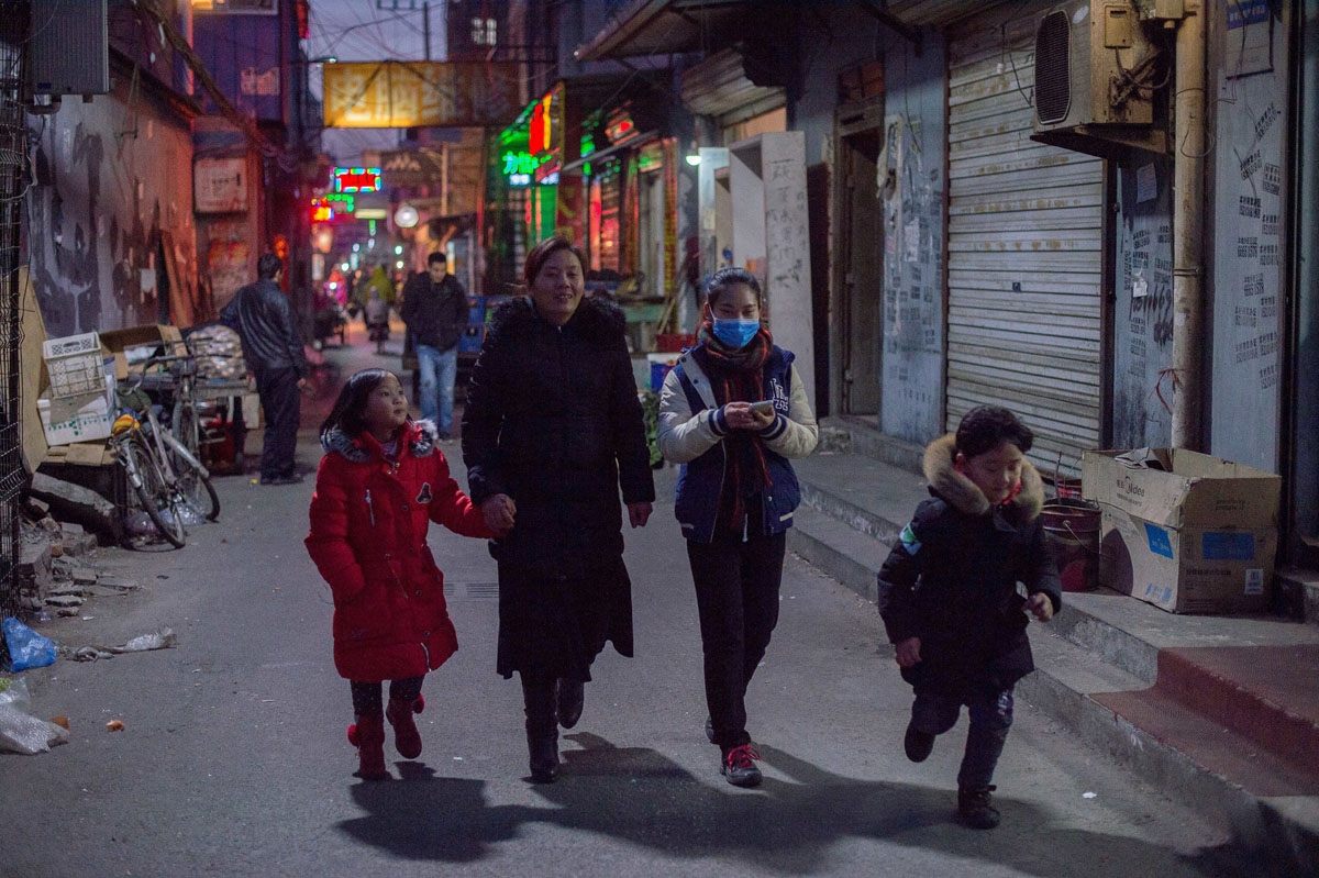 This picture taken on February 16, 2017 shows people walking on a street in the Heiqiaocun migrant village in Beijing.