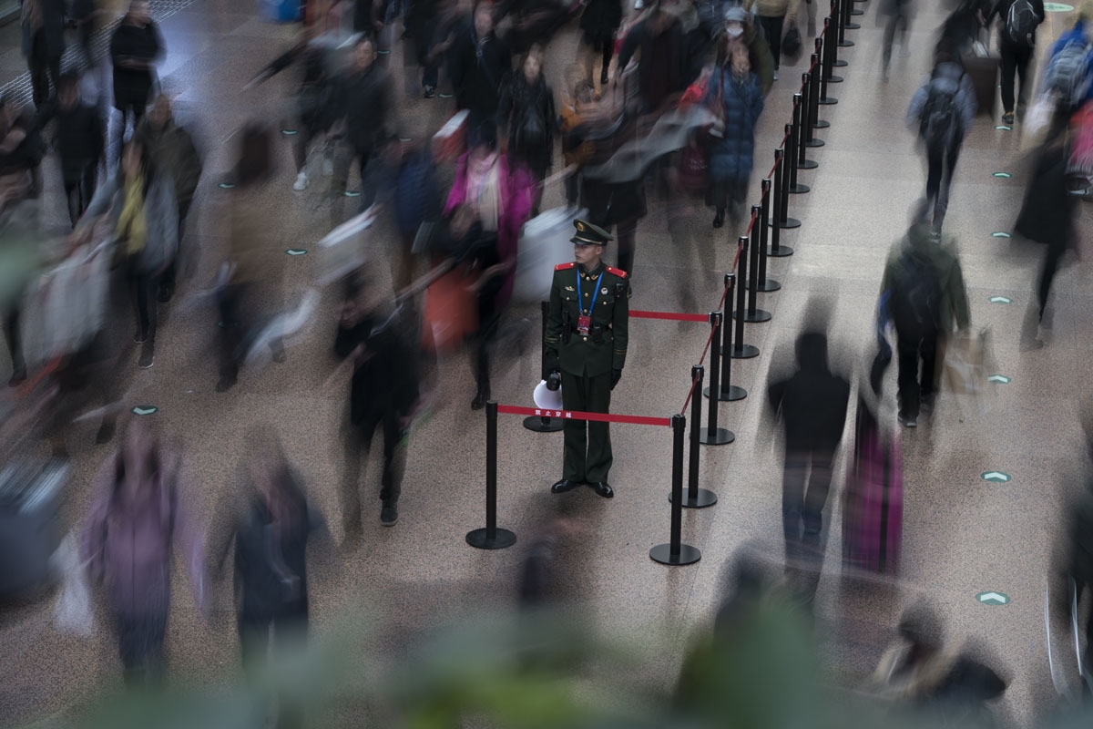 This photo taken on February 10, 2018 shows a Chinese soldier standing in the main hall while travellers rush before boarding trains at the West Railway Station in Beijing, as people depart the capital ahead of the Lunar New Year.