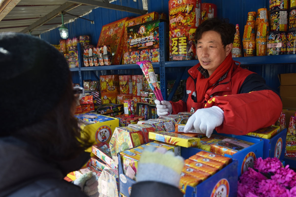 A woman buys firworks at a stall on the outskirts of Beijing in the build-up to Lunar New Year celebrations on February 13, 2018. Beijing has banned fireworks in central city areas during the Lunar New Year holiday in an effort to reduce air pollution and
