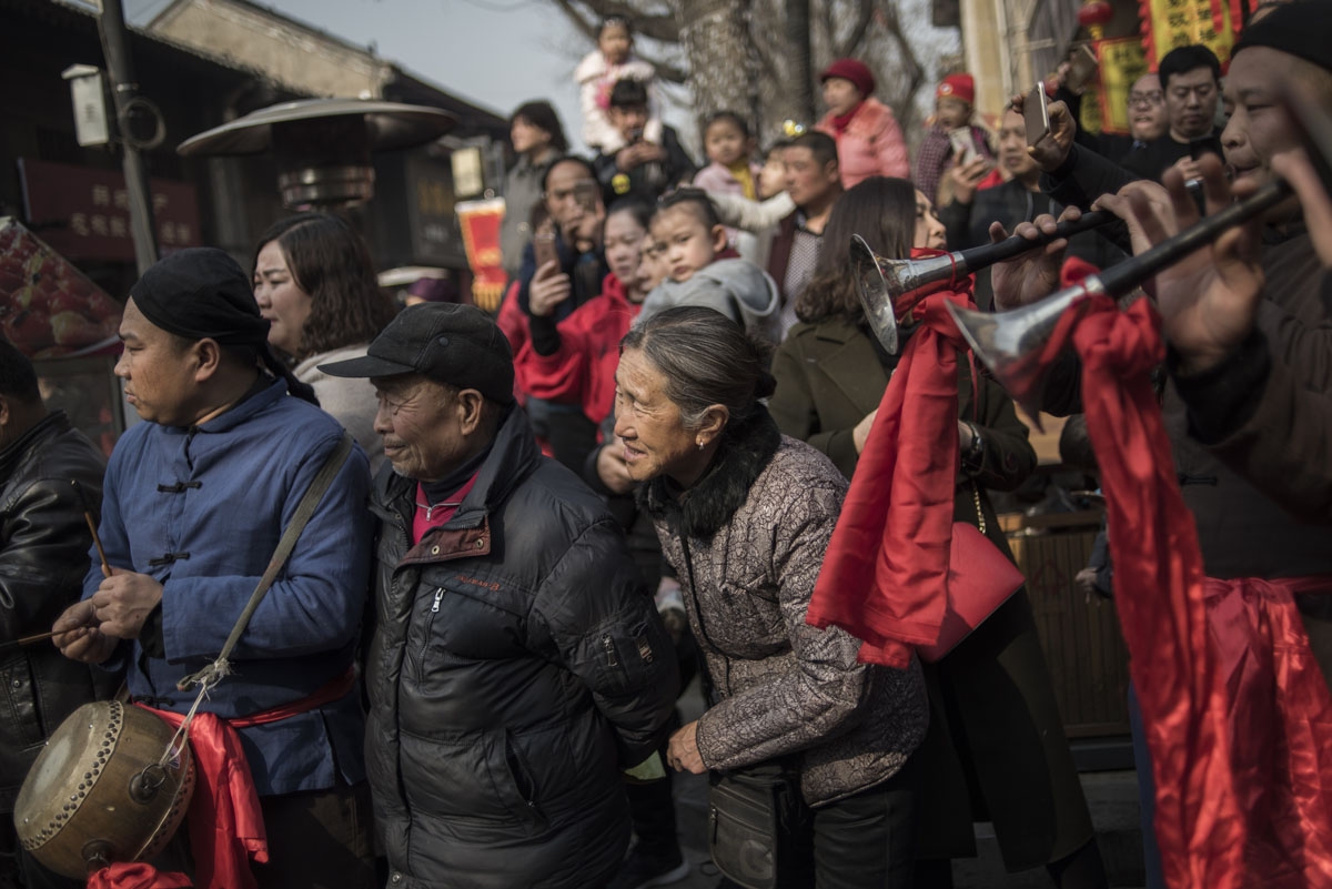 Chinese tourists look at a wedding performance as part of the She Huo festival, to celebrate the Lunar New Year, marking the Year of the Dog, in Hancheng, Shaanxi province, on February 16, 2018.