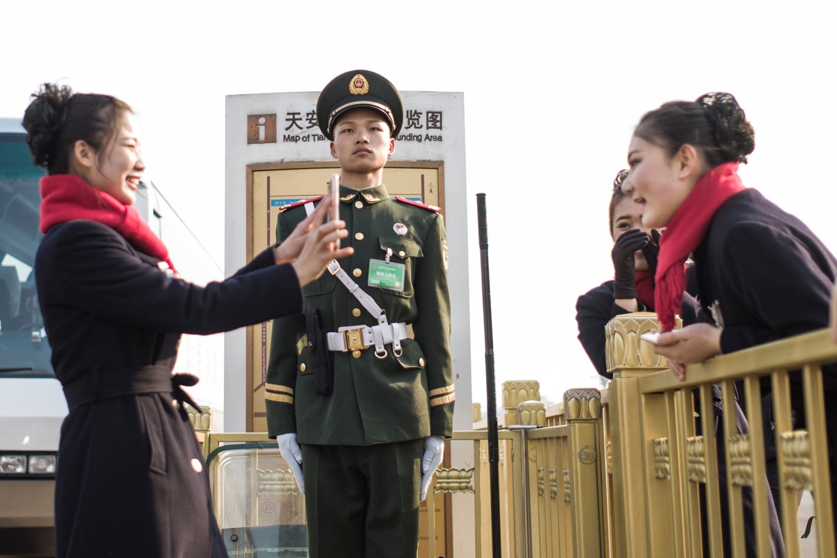 Hostesses take pictures next to a paramilitary guard during the opening session of the Chinese People's Political Consultative Conference (CPPCC) in the Great Hall of the People in Beijing on March 3, 2017.
