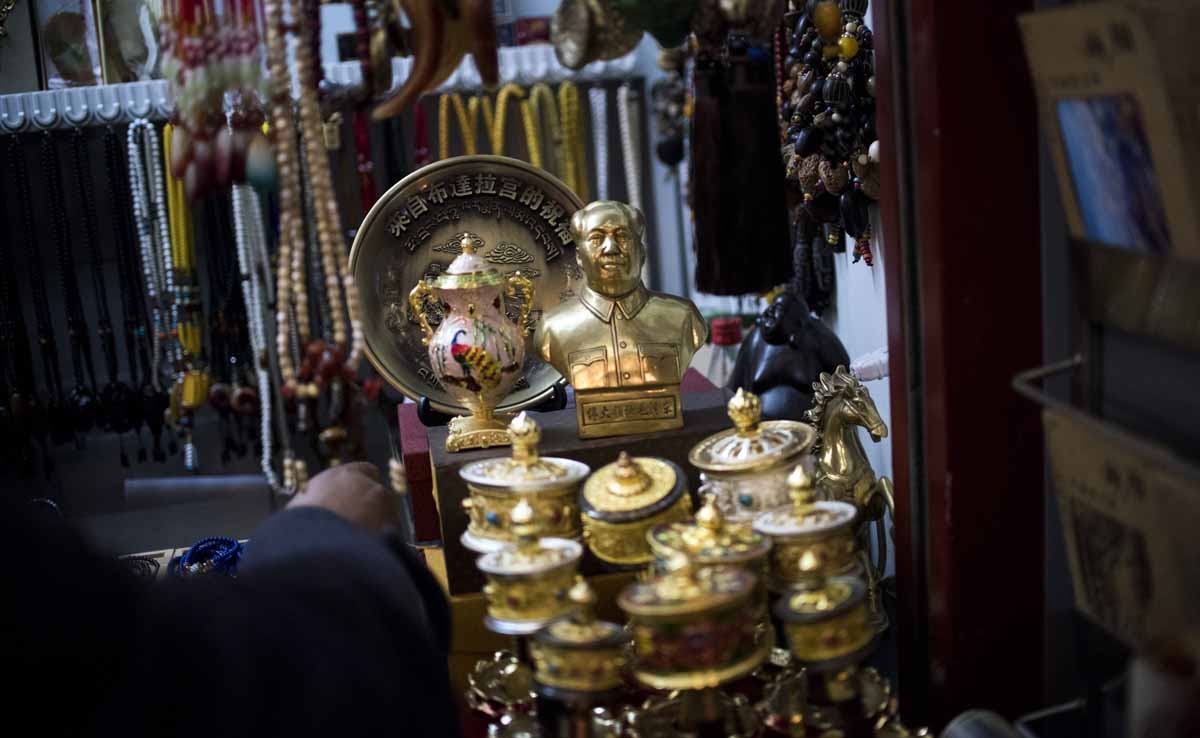 This picture taken on September 11, 2016 shows prayer wheels and Mao statues displayed for sale at a stall next the iconic Potala Palace in the regional capital Lhasa, in China's Tibet Autonomous Region. This picture taken on September 11, 2016 shows prayer wheels and Mao statues displayed for sale at a stall next the iconic Potala Palace in the regional capital Lhasa, in China's Tibet Autonomous Region.