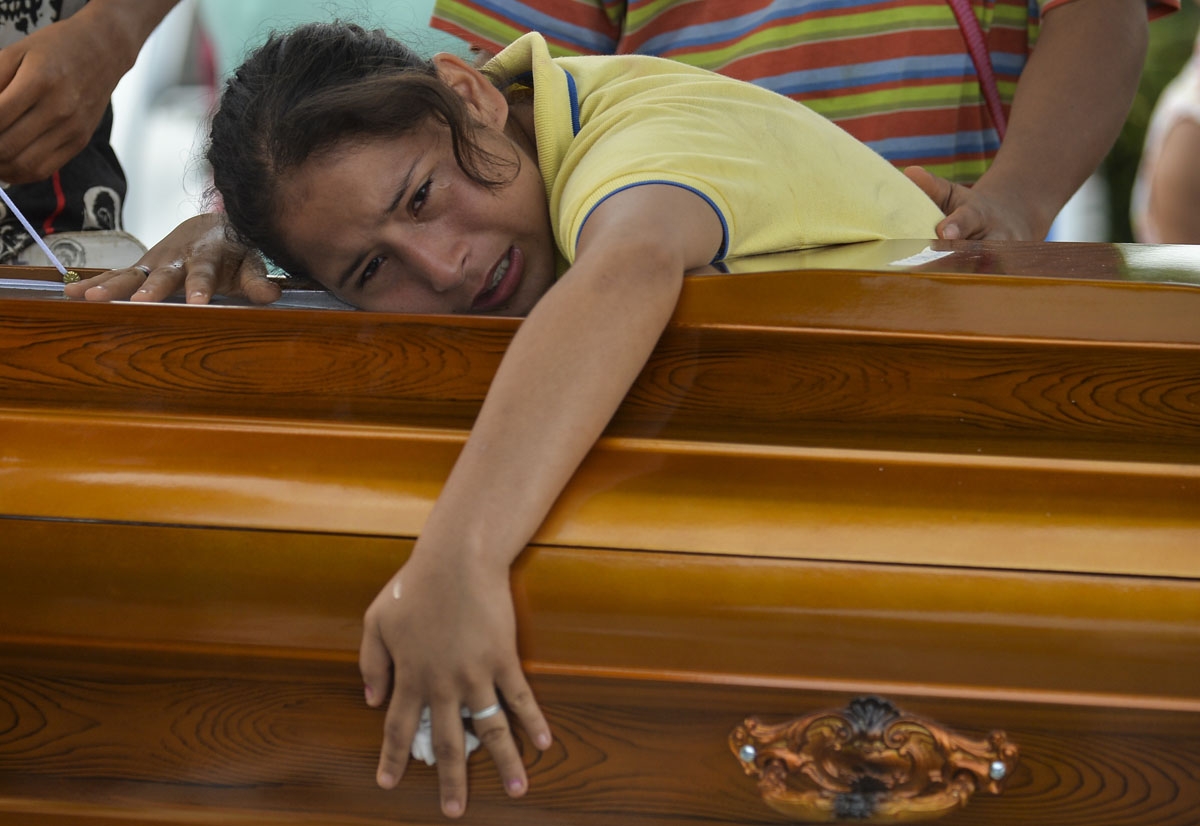 A woman mourns over the coffin of her father killed by a mudslide caused by heavy rains, at the cemetery in Mocoa, Putumayo department, Colombia on April 3, 2017.