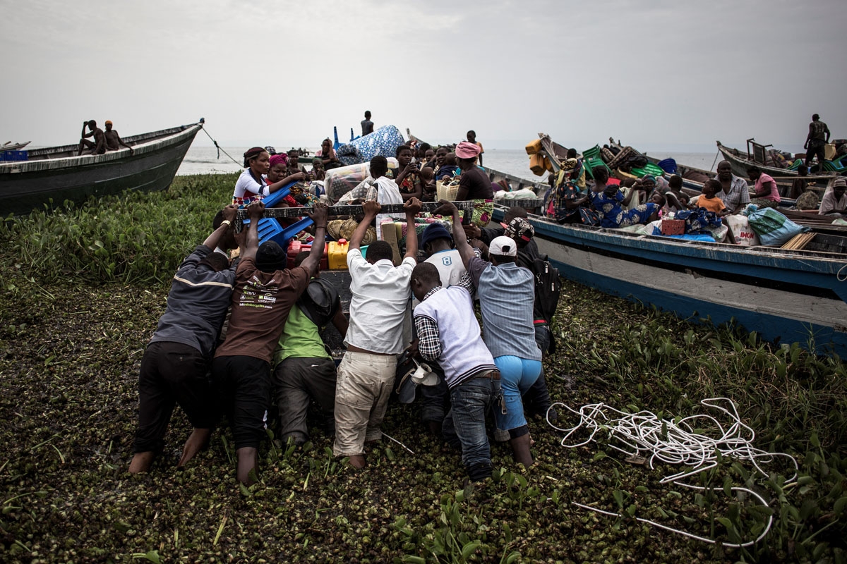 Internally displaced Congolese push a boat in Tchomia out onto Lake Albert, in a bid to cross into Uganda on the other side. March 5, 2018.