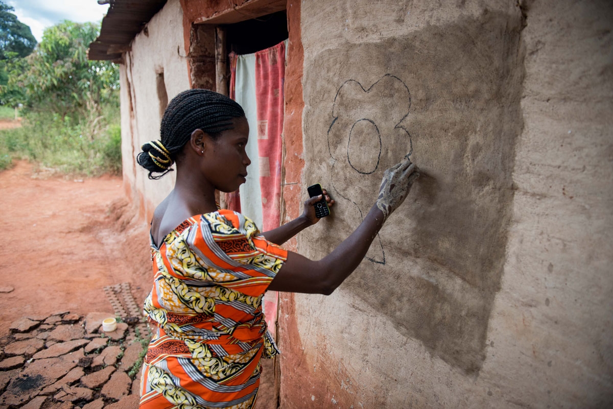 This photograph taken on May 13, 2017, shows villager Josephine Muloba painting a hut with her hands in Makwatsha, DR Congo.