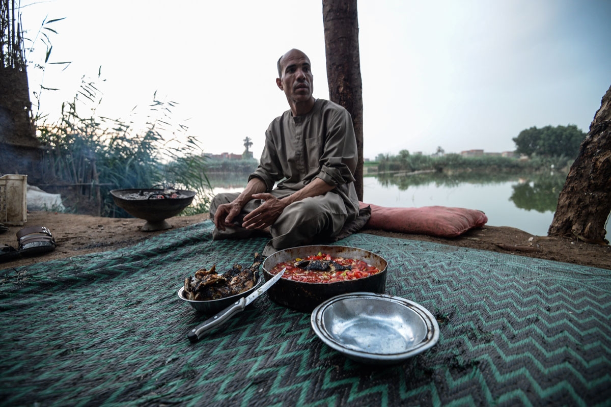 An Egyptian Fisherman prepares for a meal by the Pharaonic Sea, in the village of Kafr Fisha, province of Munuf, on June 16, 2018.