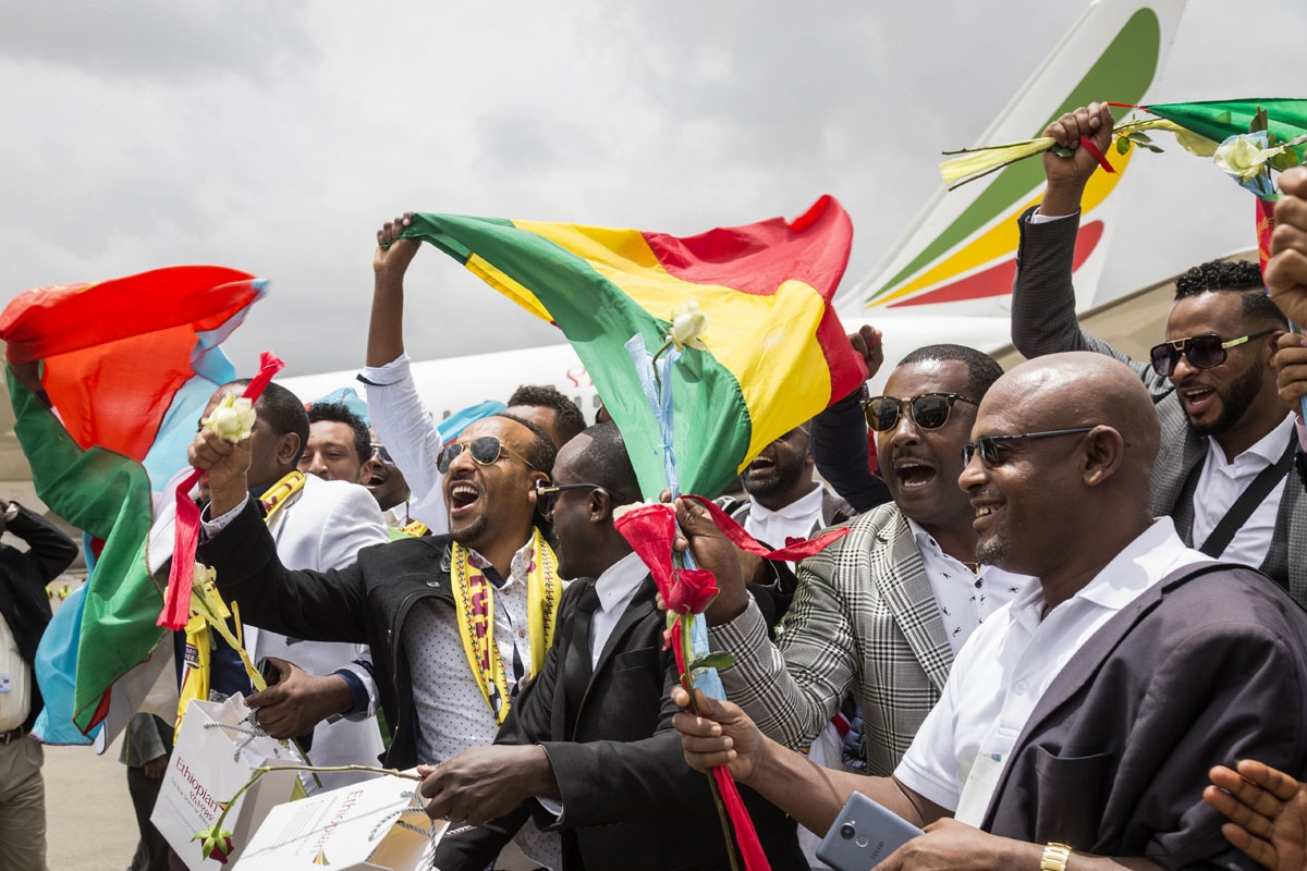 Passengers carrying Ethiopian and Eritrean flags celebrate on the tarmac upon their arrival at the Asmara International airport, on July 18, 2018.