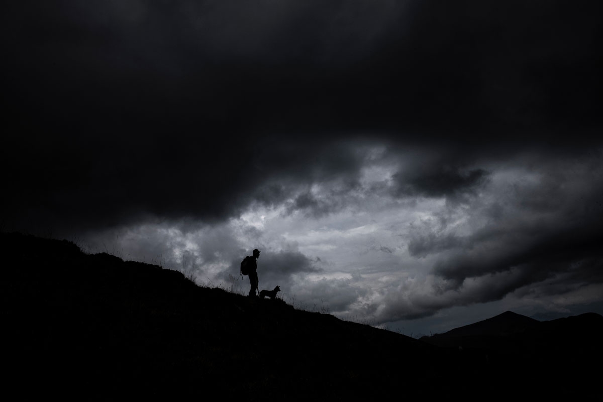 French shepherd Gaetan Meme, 24-years-old, looks over a flock of sheep as the weather turns stormy, on August 21, 2018, along the Alpine pastures in the mountains near the Col du Glandon, in the French Alps. - Gaetan shepherds a flock of 1,300 sheep in th