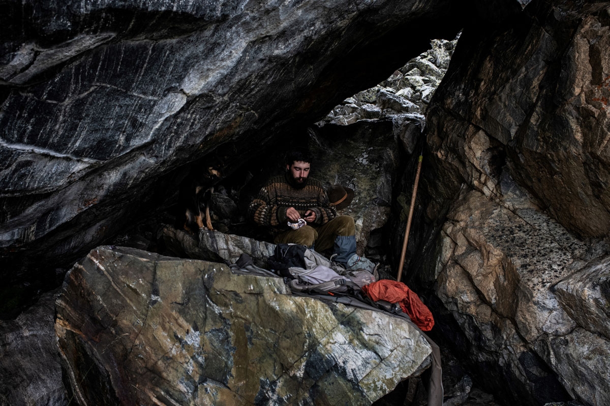 French shepherd Gaetan Meme, 24-years-old, takes cover from the storm in a cave with his dog Leica, on August 21, 2018, along the Alpine pastures in the mountains near the Col du Glandon, in the French Alps. - Gaetan shepherds a flock of 1,300 sheep in th