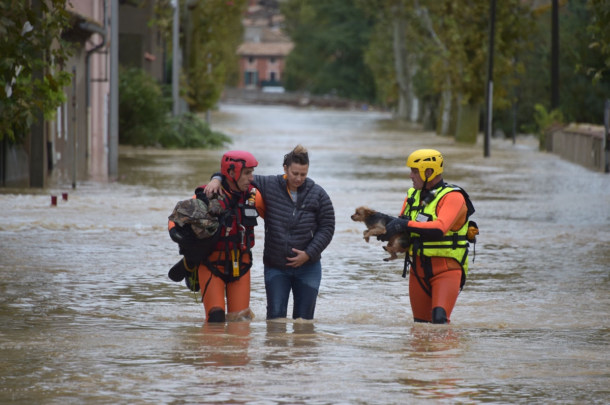 Firefighters helps a resident with a dog following heavy rains that saw rivers bursting banks on October 15, 2018 in Trebes, near Carcassone, southern France. - Six people died following storm and flash floods during the night of October 15 in the Aude de
