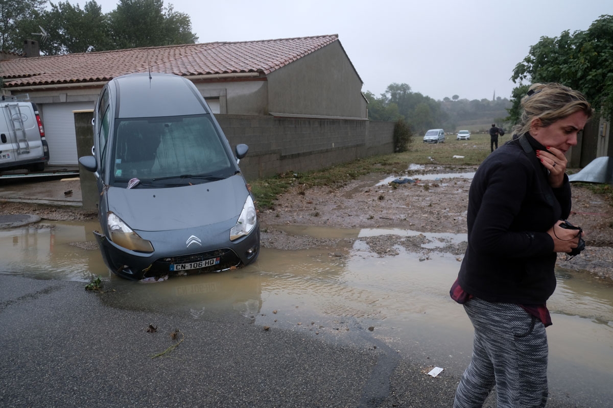 People walk by damages in a street of Villegailhenc in the Aude department after it was particularly badly hit by heavy rain storms which swamped parts of southwestern France, flooding rivers and cutting roads, killing at least six people. - The Aude rive