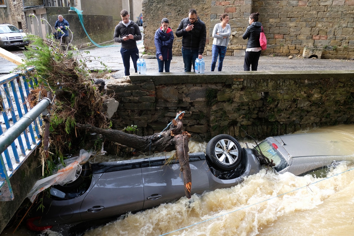 Residents look at damaged cars on the Trapel river following heavy rains that saw rivers bursting banks on October 15, 2018 in Villegailhenc, near Carcassone, southern France. - At least 13 people died as violent rainstorms turned rivers into raging torre