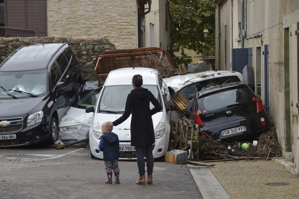 People look at damaged cars following heavy rains that saw rivers bursting banks on October 15, 2018 in Villegailhenc, near Carcassonne, southern France. - At least 13 people