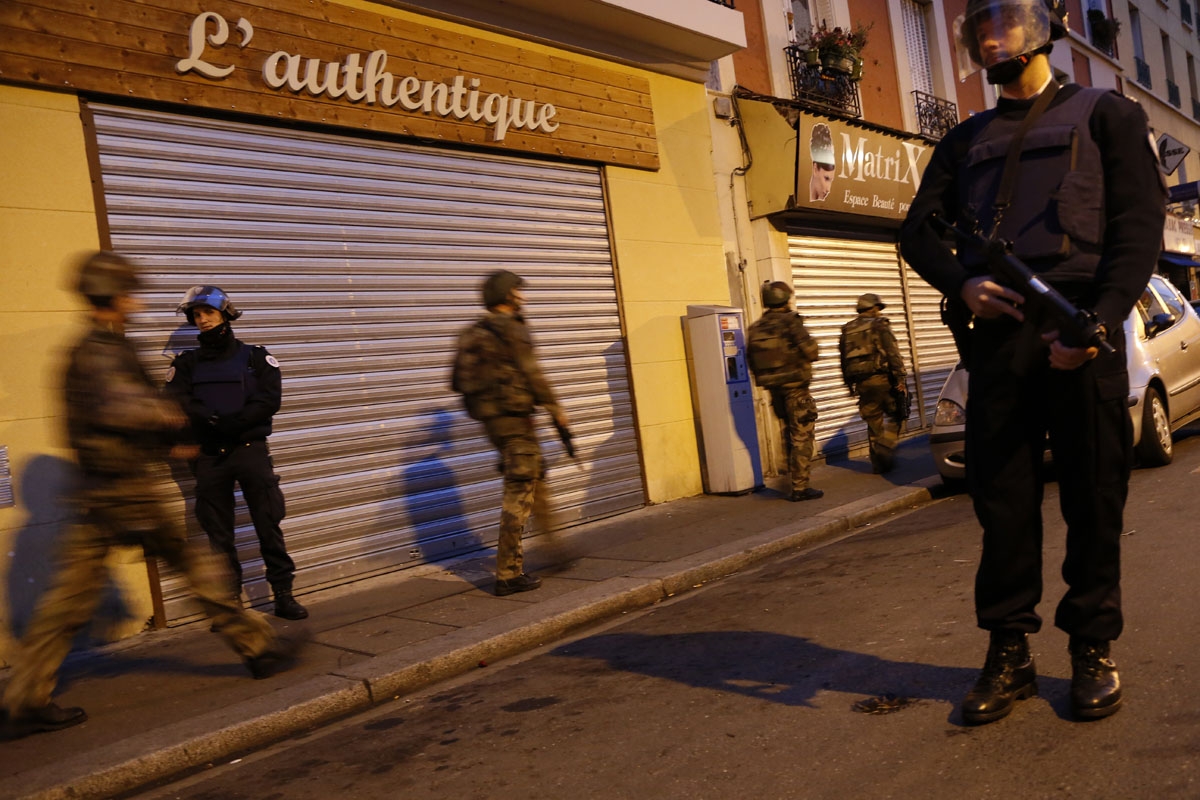 French policemen stand guard as French soldiers take combat position in the northern Paris suburb of Saint-Denis city center, on November 18, 2015, as French Police special forces raid an appartment, hunting those behind the attacks that claimed 129 lives