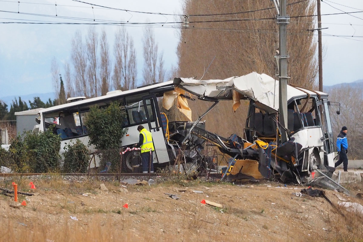 Au lendemain de la collision, le 15 décembre au matin, près de la voie ferrée. A towing service worker and a gendarme walk next to the wreckage of school bus in Millas, near Perpignan, southern France, on December 15, 2017, a day after an accident when a train crashed into the school bus at a level crossing.