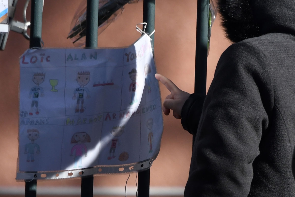 A little girl touches a drawing placed in front of the City Hall of Saint-Feliu-D'Avall after a ceremony on December 17, 2017 in memory of the five children killed in a collision between a train and a school bus on December 14.