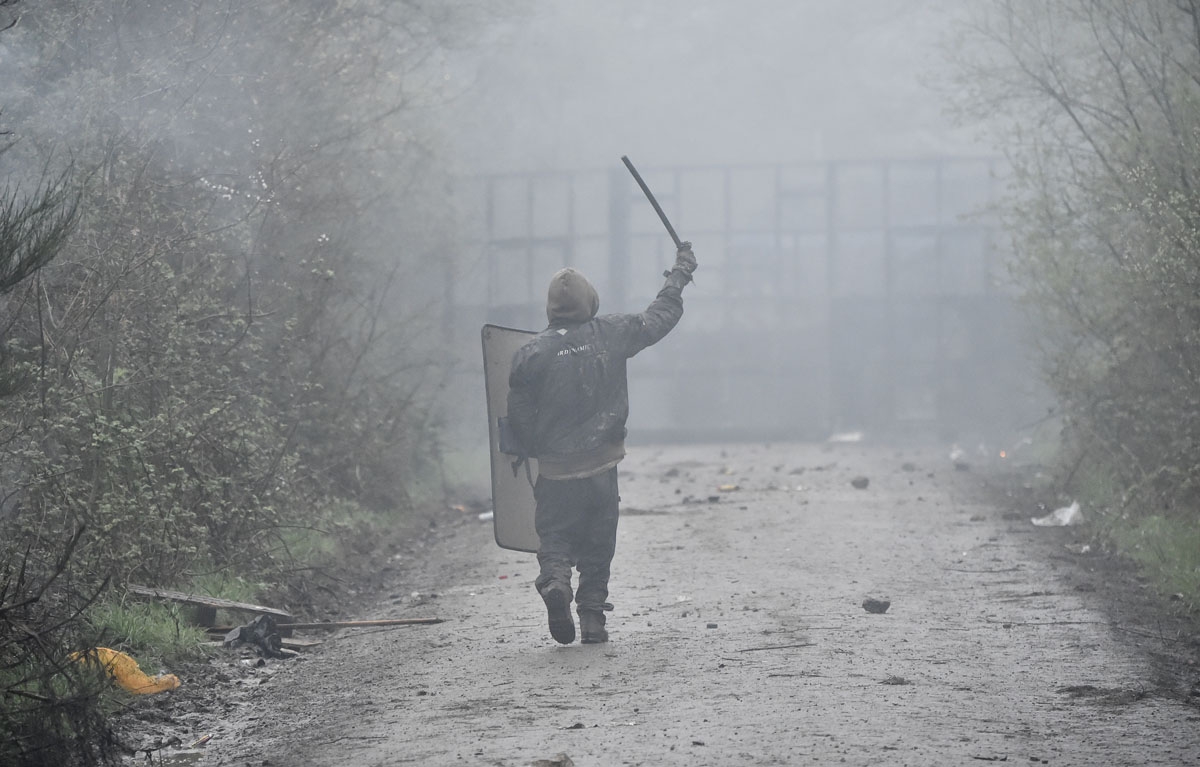 A protestor holds a police riot shield and a baton as French police officers move in to clear the area during the eviction of environmental protesters from the site, known as ZAD (Zone a Defendre - Zone to defend) of what had been a proposed new airport i