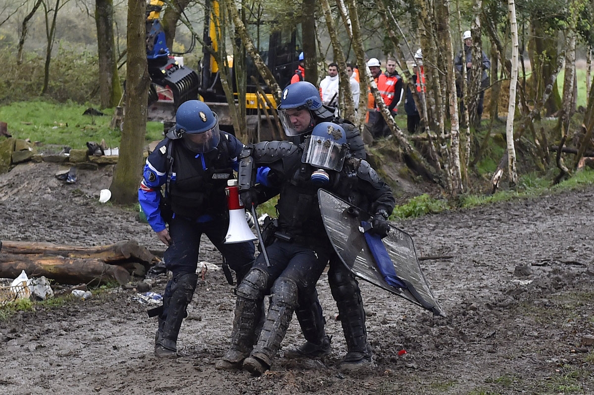An injured riot gendarme is helped by comrades when clashes erupt with protesters on April 10, 2018 during a police operation to raze the decade-old camp known as ZAD (Zone a Defendre - Zone to defend) at Notre-Dame-des-Landes, near the western city of Na