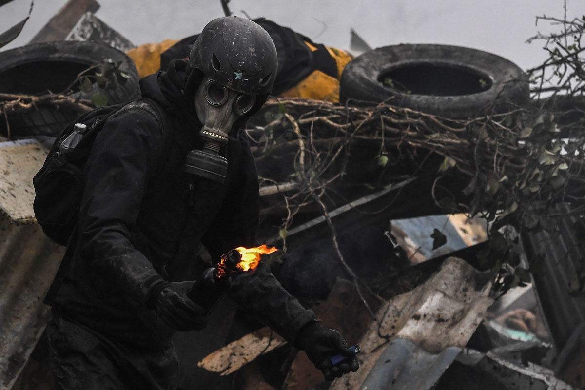 A protester is about to throw a Molotov cocktail at riot forces as clashes erupt on April 10, 2018 during a police operation to raze the decade-old camp known as ZAD (Zone a Defendre - Zone to defend) at Notre-Dame-des-Landes, near the western city of Nan