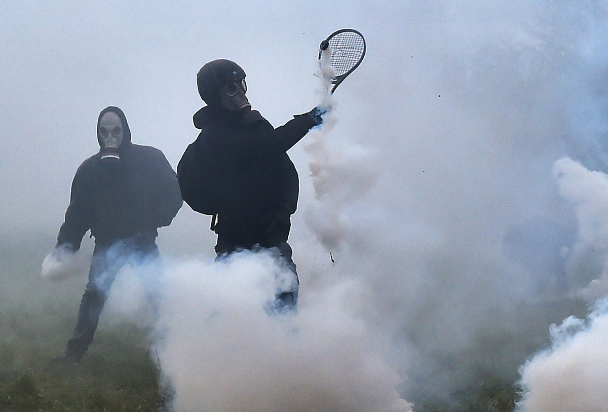 A protester uses a tennis racquet to defend himself from teargas canisters released by riot forces as clashes erupt during a police operation to raze the decade-old camp known as ZAD (Zone a Defendre - Zone to defend) at Notre-Dame-des-Landes, near the we