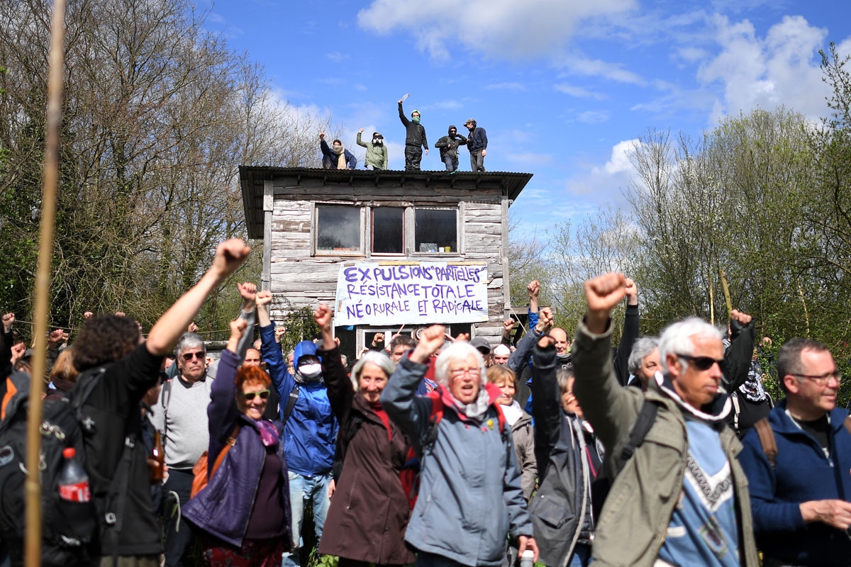 Protesters raise their fists on April 11, 2018, during a police operation to raze the decade-old anti-capitalist camp known as ZAD (Zone a Defendre - Zone to defend) set up to protest a new airport in Notre-Dame-des-Landes, near the western French city