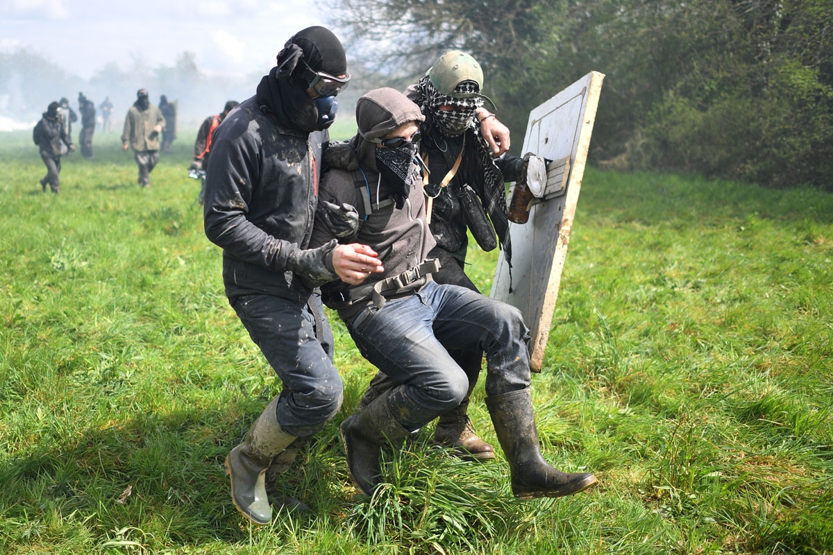 An injured protester is evacuated by fellow protesters while clashing with gendarmes on April 11, 2018, during a police operation to raze the decade-old anti-capitalist camp known as ZAD (Zone a Defendre - Zone to defend) set up to protest a new airport