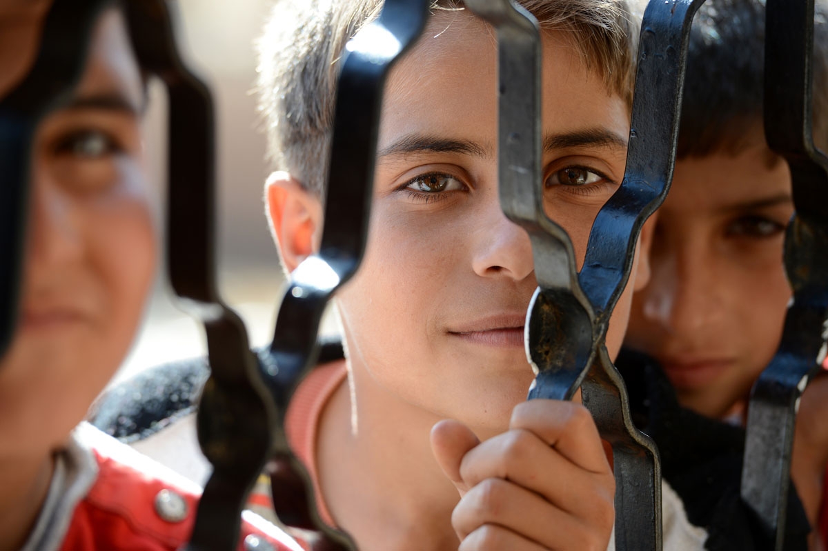 Syrian boys wait for food behind an iron door at a school housing around 140 refugees in the village of Atme in the Idlib province near the border with Turkey on November 6, 2012. Syrian boys wait for food behind an iron door at a school housing around 140 refugees in the village of Atme in the Idlib province near the border with Turkey on November 6, 2012.