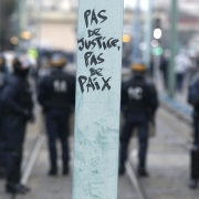 Anti riot police stands guard in front of graf reading No justice no peace in Bobigny, northern Paris, on February 16, 2017 during a demonstration to demand justice for Theo, a 22-year-old youth worker who required surgery after his arrest last week in th