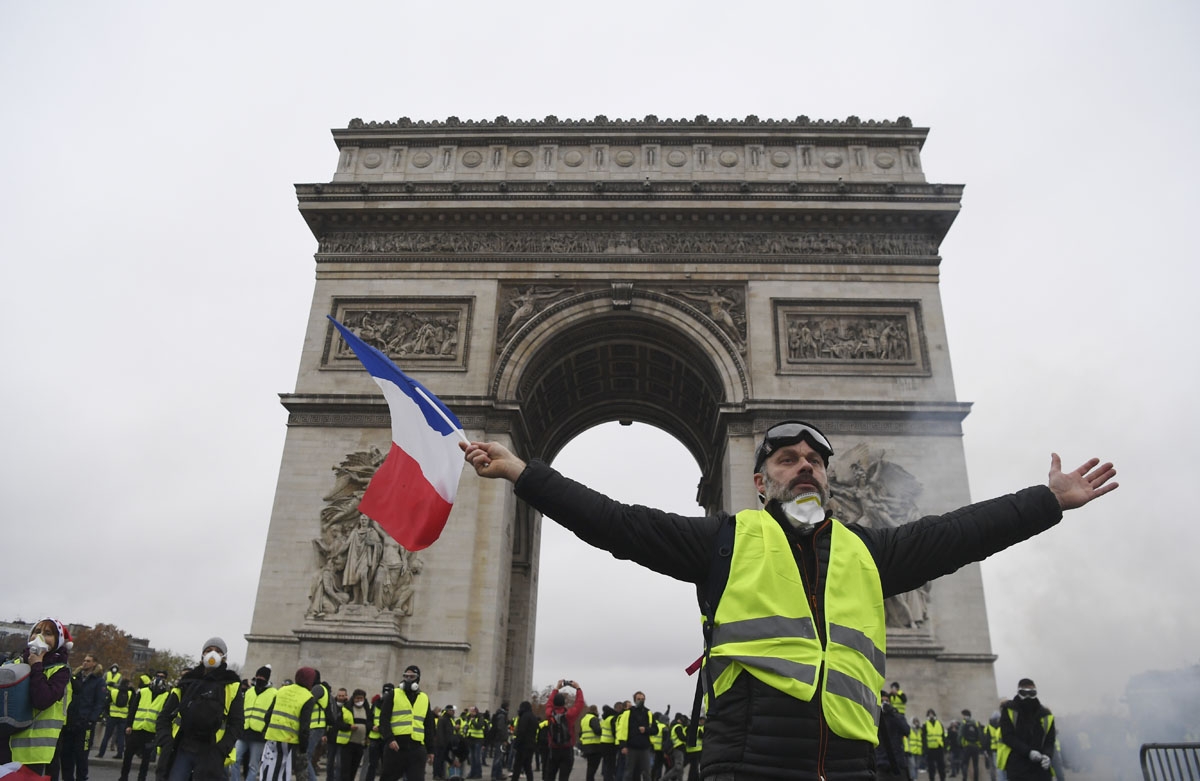 A demonstrator waves a French national flag during a protest of Yellow vests (Gilets jaunes) against rising oil prices and living costs in front of the Arc of Triomphe on the Champs Elysees avenue in Paris, on December 1, 2018. - Thousands of anti-governm
