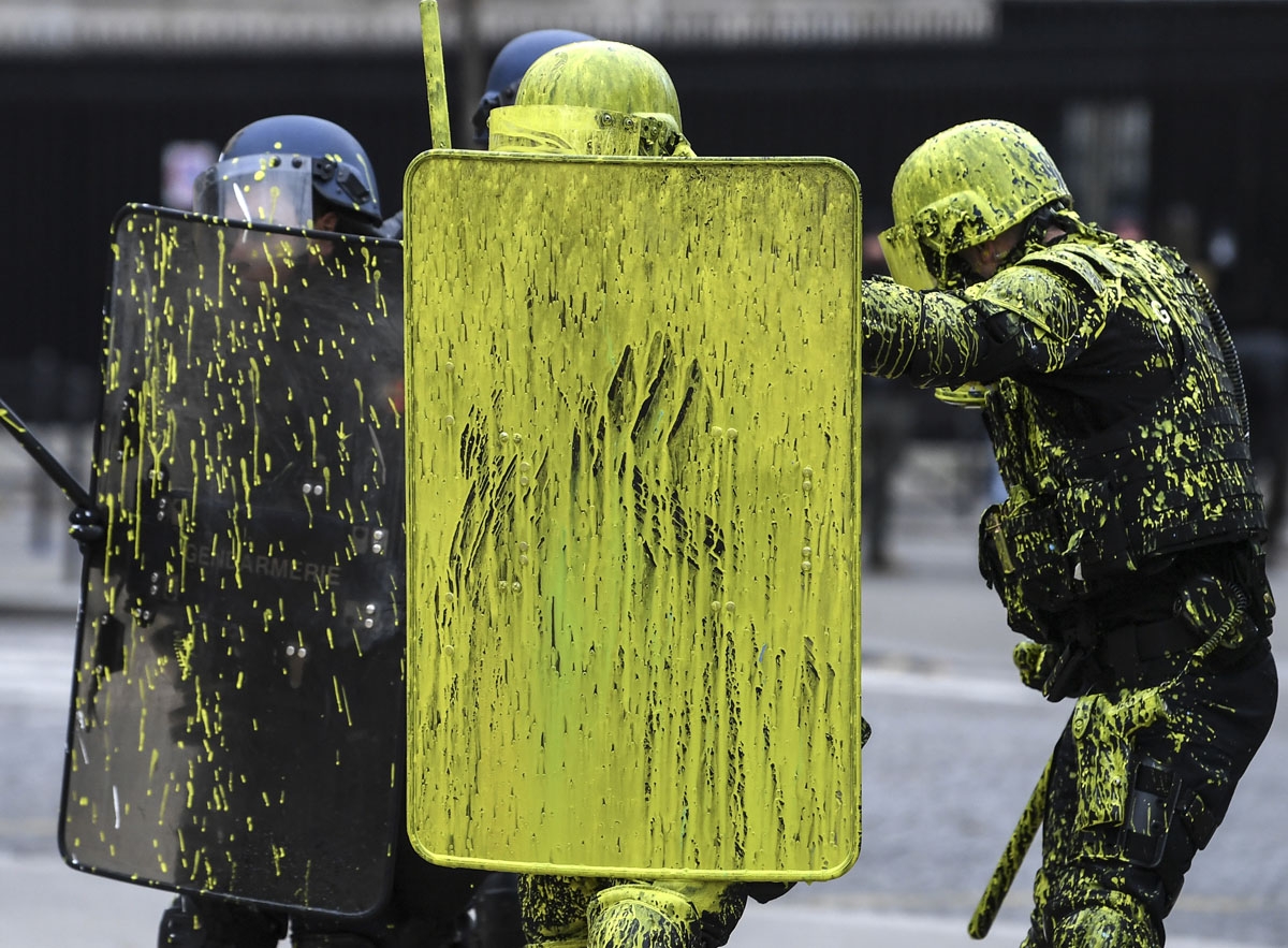 Riot police officers are covered with painting during clashes with demonstrators as part of a protest of Yellow vests (Gilets jaunes) against rising oil prices and living costs on the Champs Elysees in Paris, on December 1, 2018. -