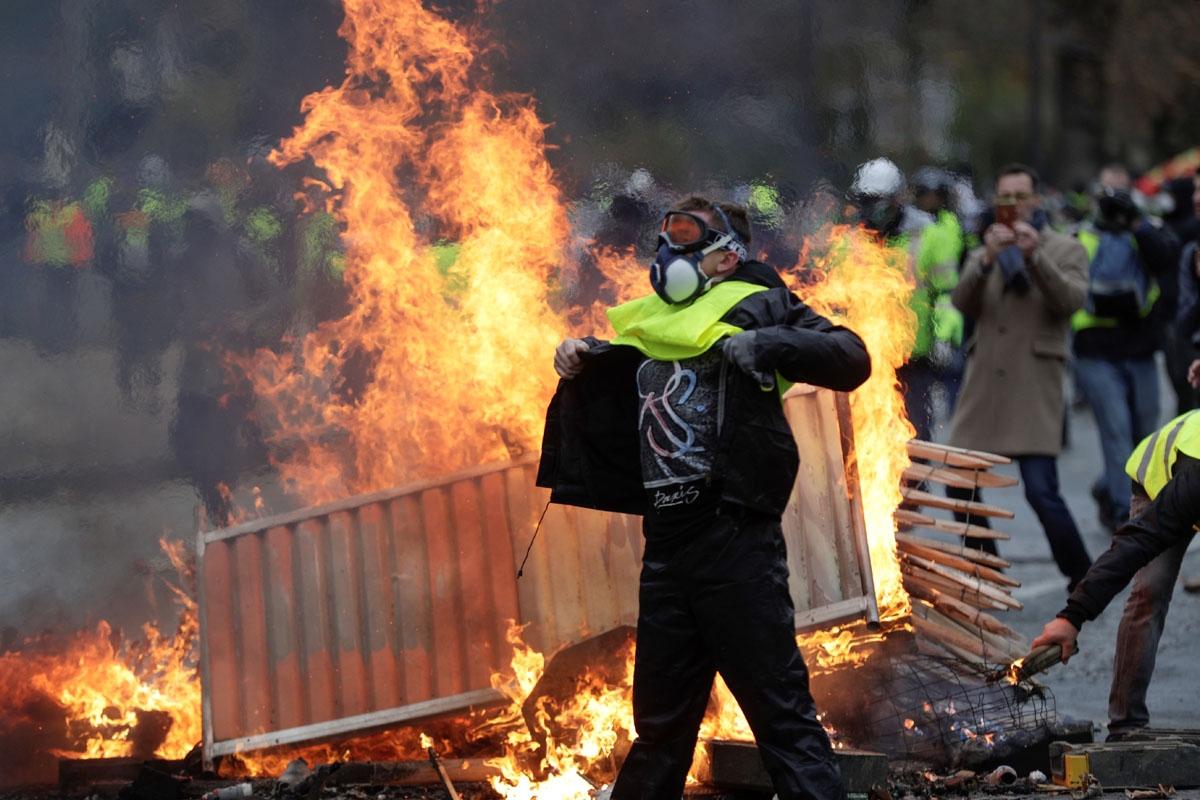 A demonstrator walks past a fire during a protest of Yellow vests (Gilets jaunes) against rising oil prices and living costs on the Champs Elysees, in Paris, on December 1, 2018. -