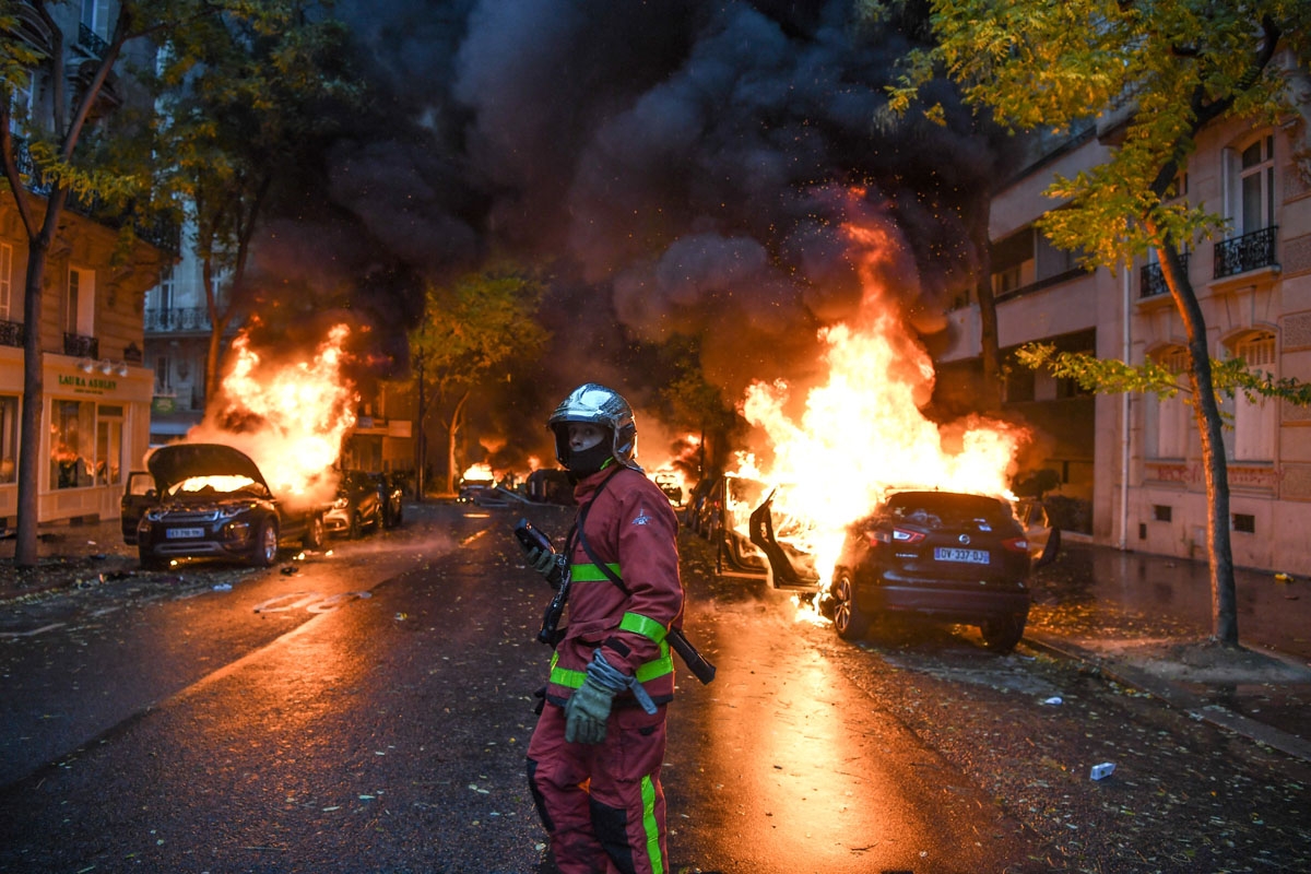 A firefighter looks on as cars are burning during a protest of Yellow vests (Gilets jaunes) against rising oil prices and living costs, on December 1, 2018 in Paris. - Speaking at the Paris police's command centre, French Prime Minister said 36,000 people