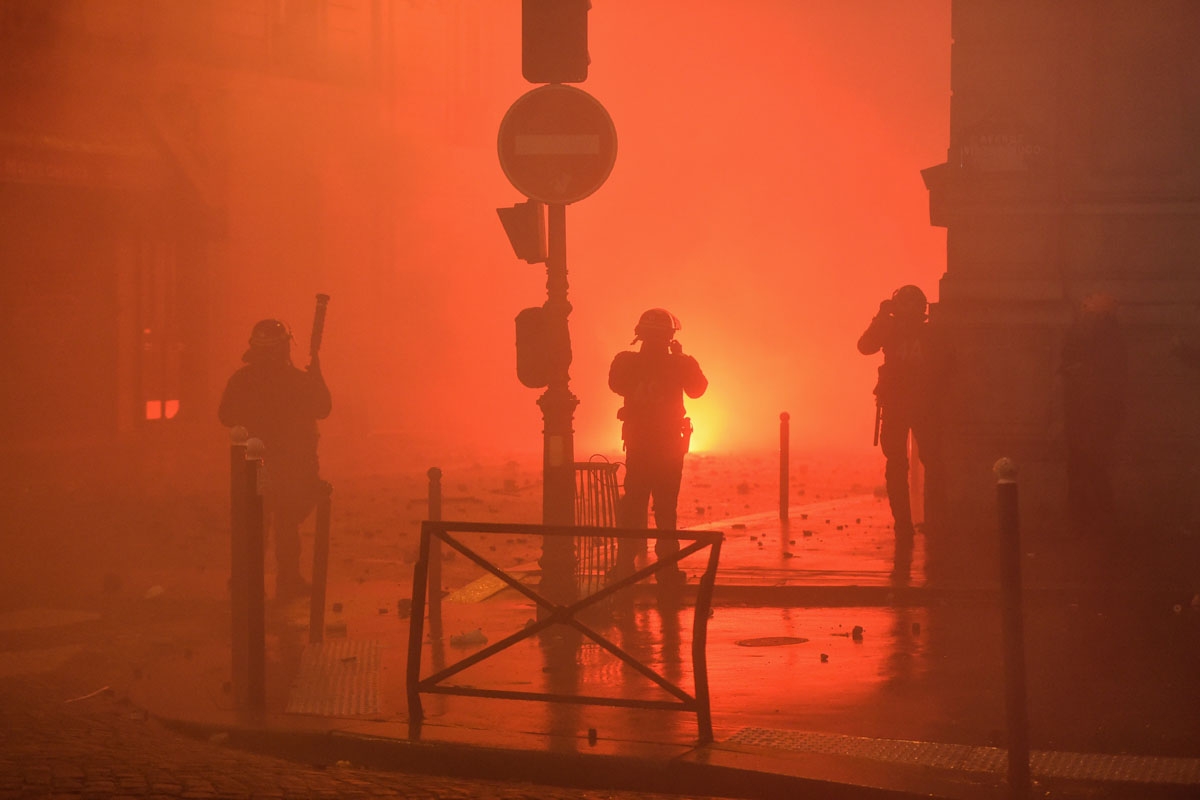 Policemen stand in front of demonstrators during a protest of Yellow vests (Gilets jaunes) against rising oil prices and living costs, on December 1, 2018 in Paris. - Speaking at the Paris police's command centre, French Prime Minister said 36,000 people