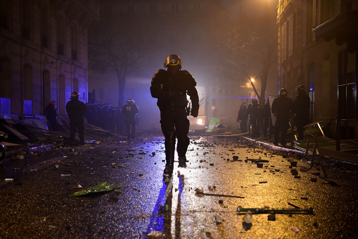 A policeman runs during a protest of Yellow vests (Gilets jaunes) against rising oil prices and living costs, on December 1, 2018 in Paris. - Speaking at the Paris police's command centre, French Prime Minister said 36,000 people were protesting across Fr