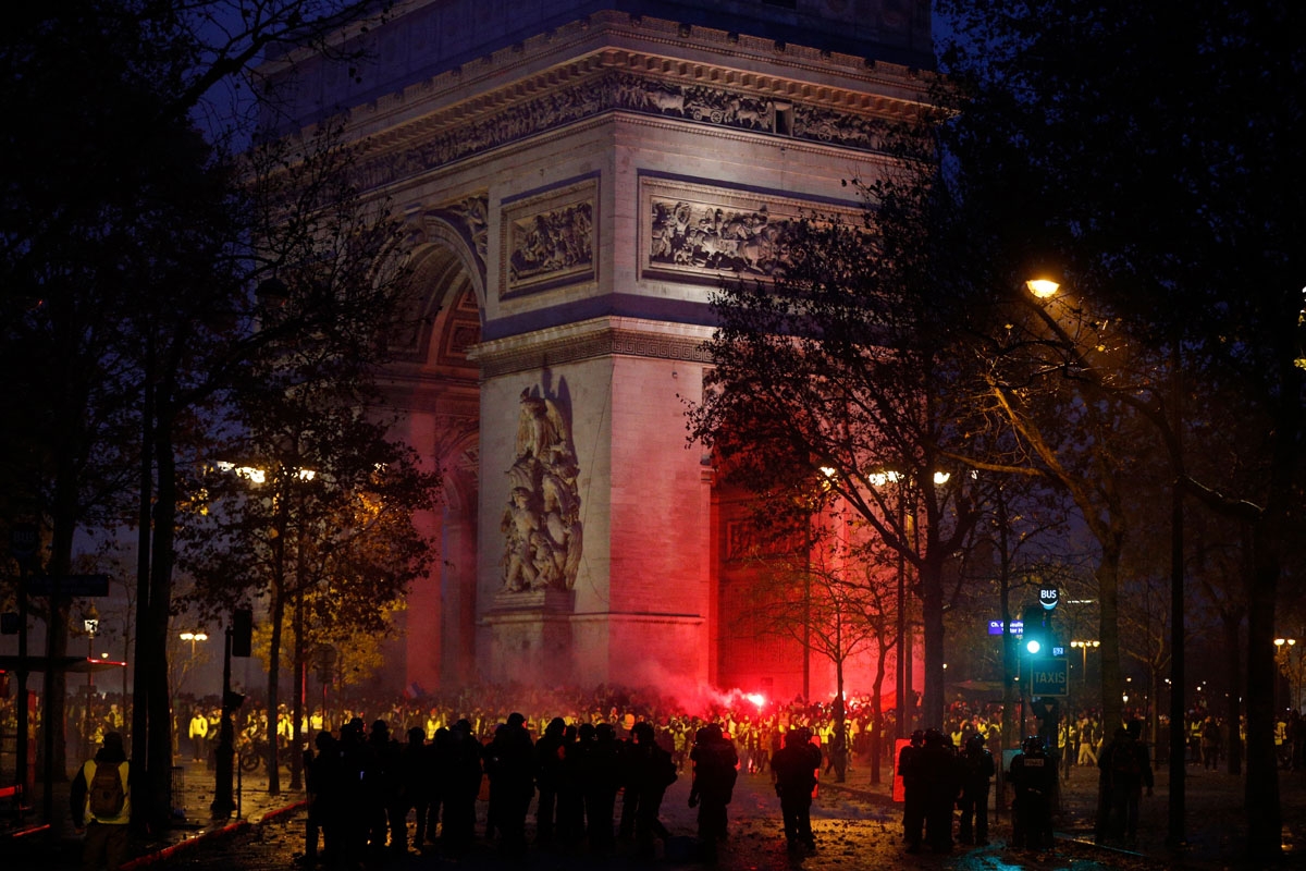 Demonstrators wearing Yellow vests (Gilets jaunes), face riot police officers during a protest against rising oil prices and living costs, in front of the Arc de Triomphe on the Champs Elysees avenue in Paris on December 1, 2018. - Police and anti-governm
