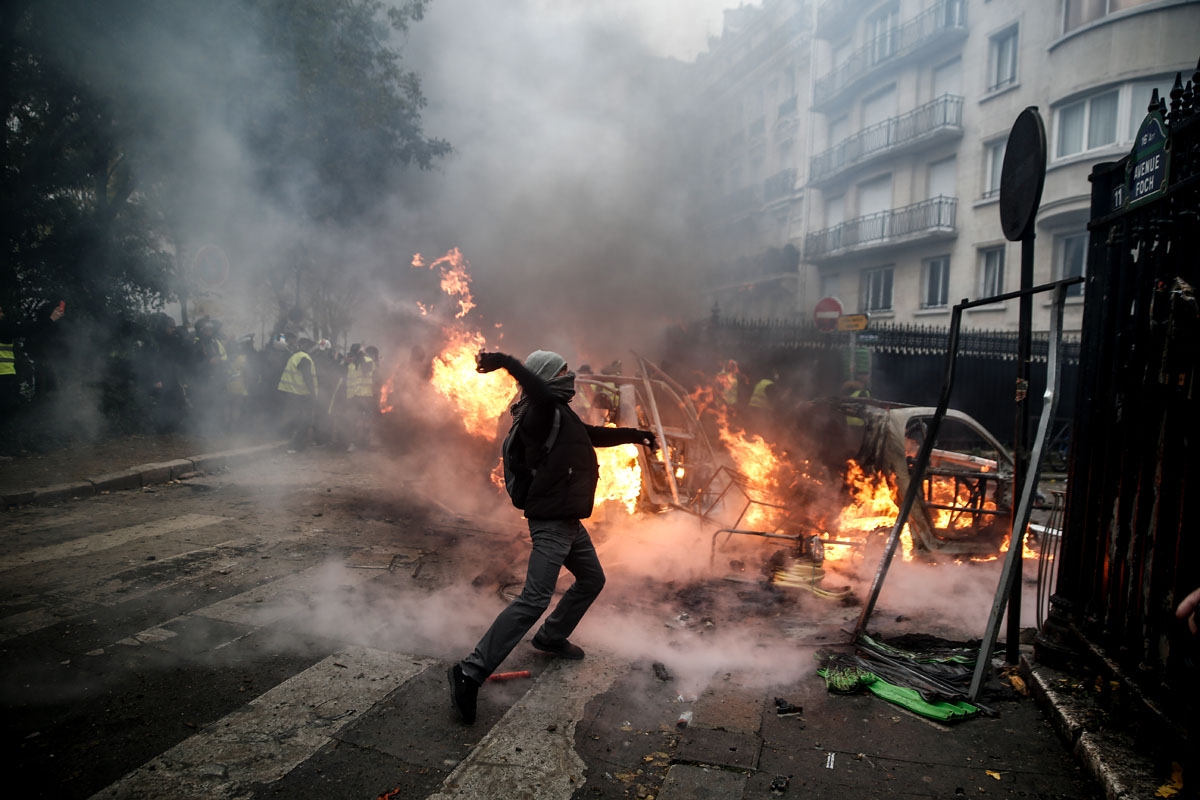A protester throws projectile at riot police during a protest of Yellow vests (Gilets jaunes) against rising oil prices and living costs, on December 1, 2018 in Paris. (